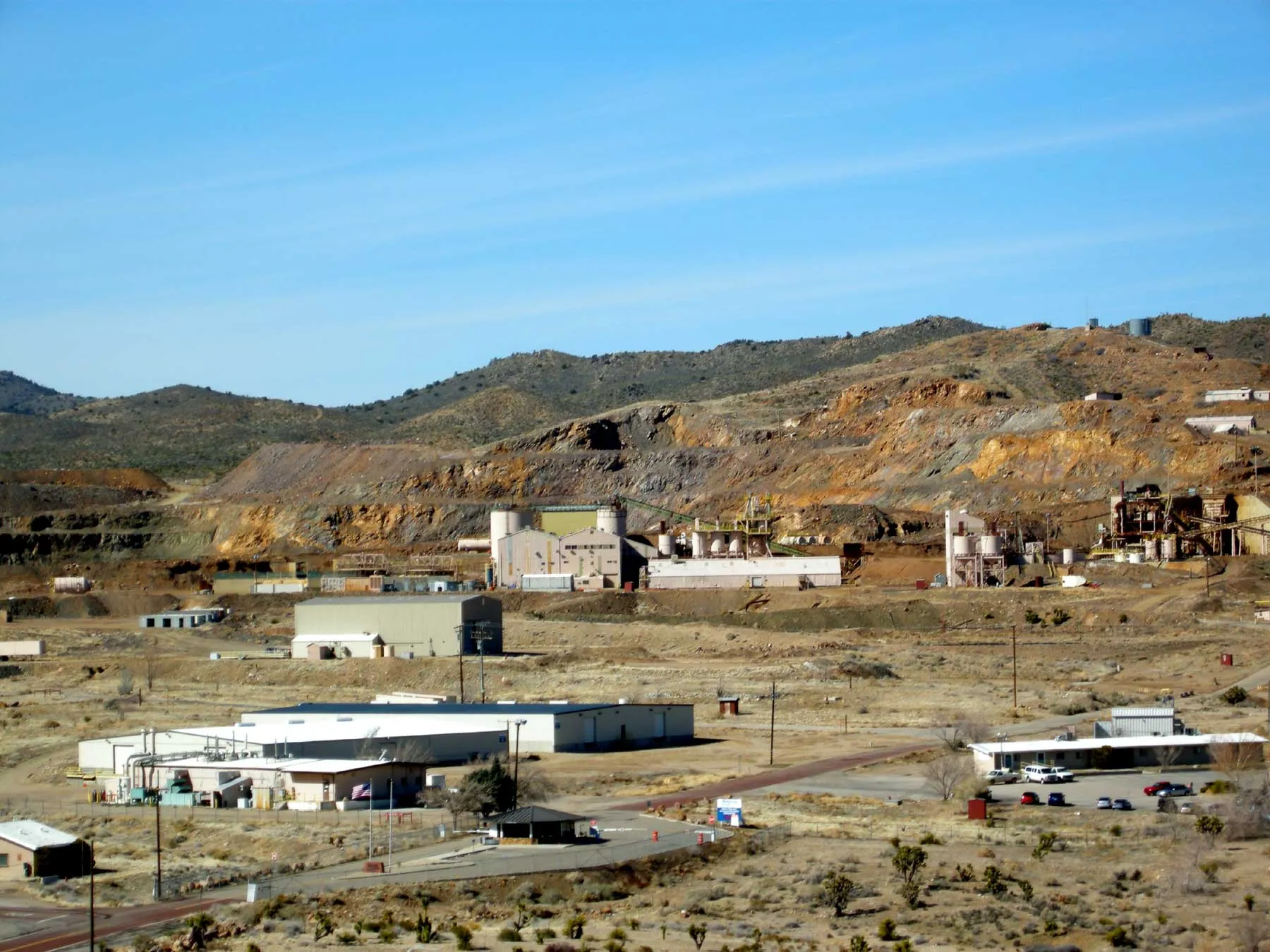 The Mountain Pass rare earth mine and processing plant in the California desert, with pale industrial buildings below excavated hillsides.